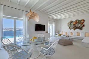 Relax in this stylish living room with a glass dining table, comfortable sofa, and stunning sea views.