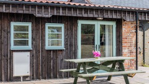 A wooden building with a tiled roof, a brick wall, and a door with a glass panel. - Hebe (Dorchester)