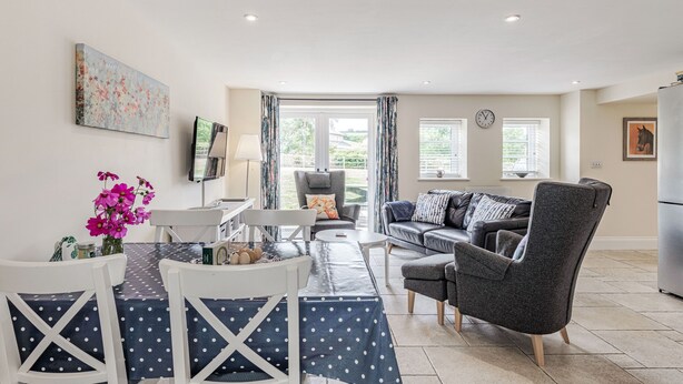 A modern living room with a dining area, featuring a sofa, chairs, a table, and a TV. - Hebe (Dorchester)