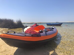 A clear shallow water area with a boat and a life jacket on the shore.