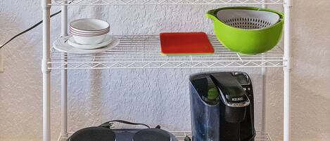 A kitchen with a microwave, toaster, and various utensils on shelves.