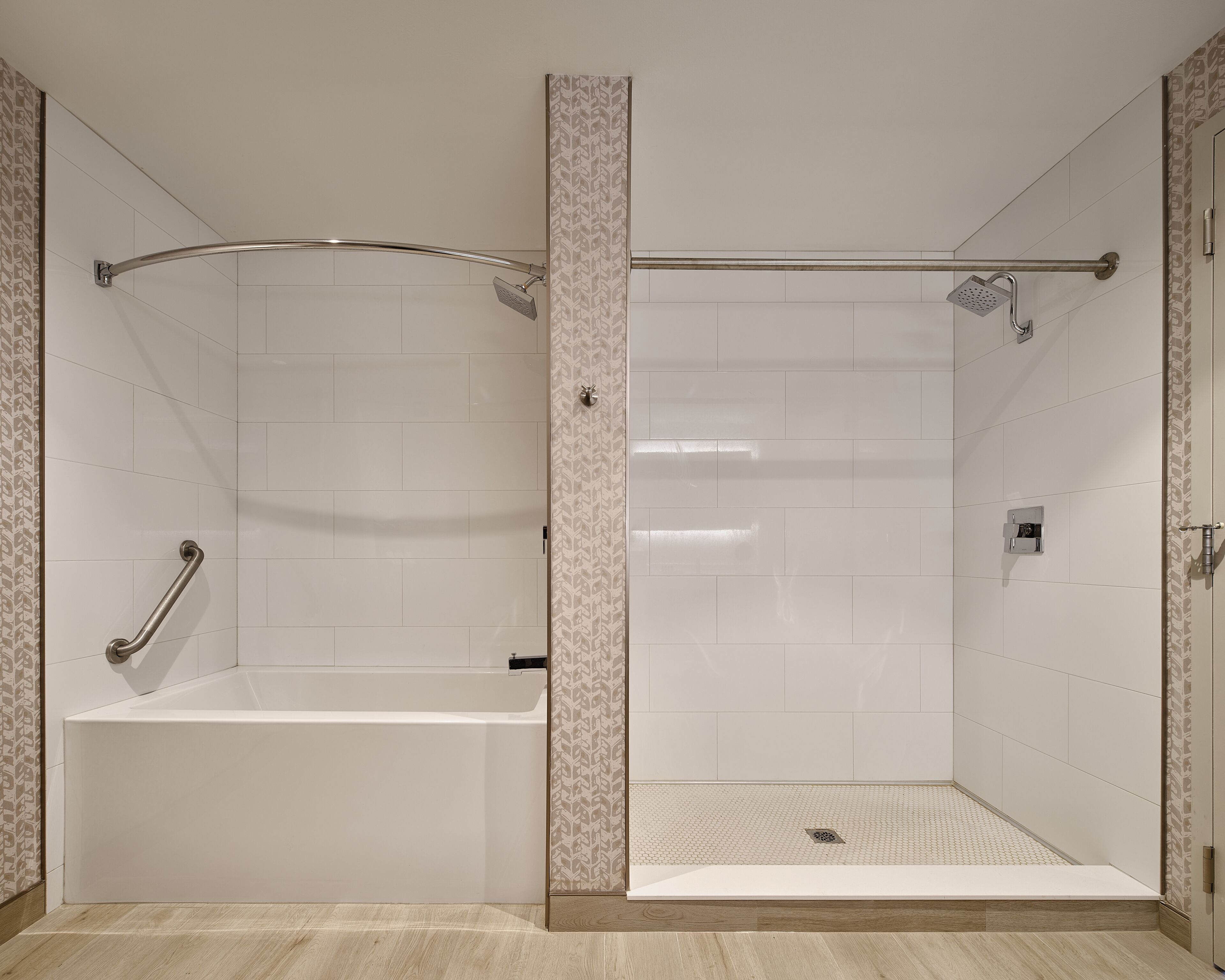 Un baño con bañera y cabina de ducha, ambos con azulejos blancos y un borde decorativo.