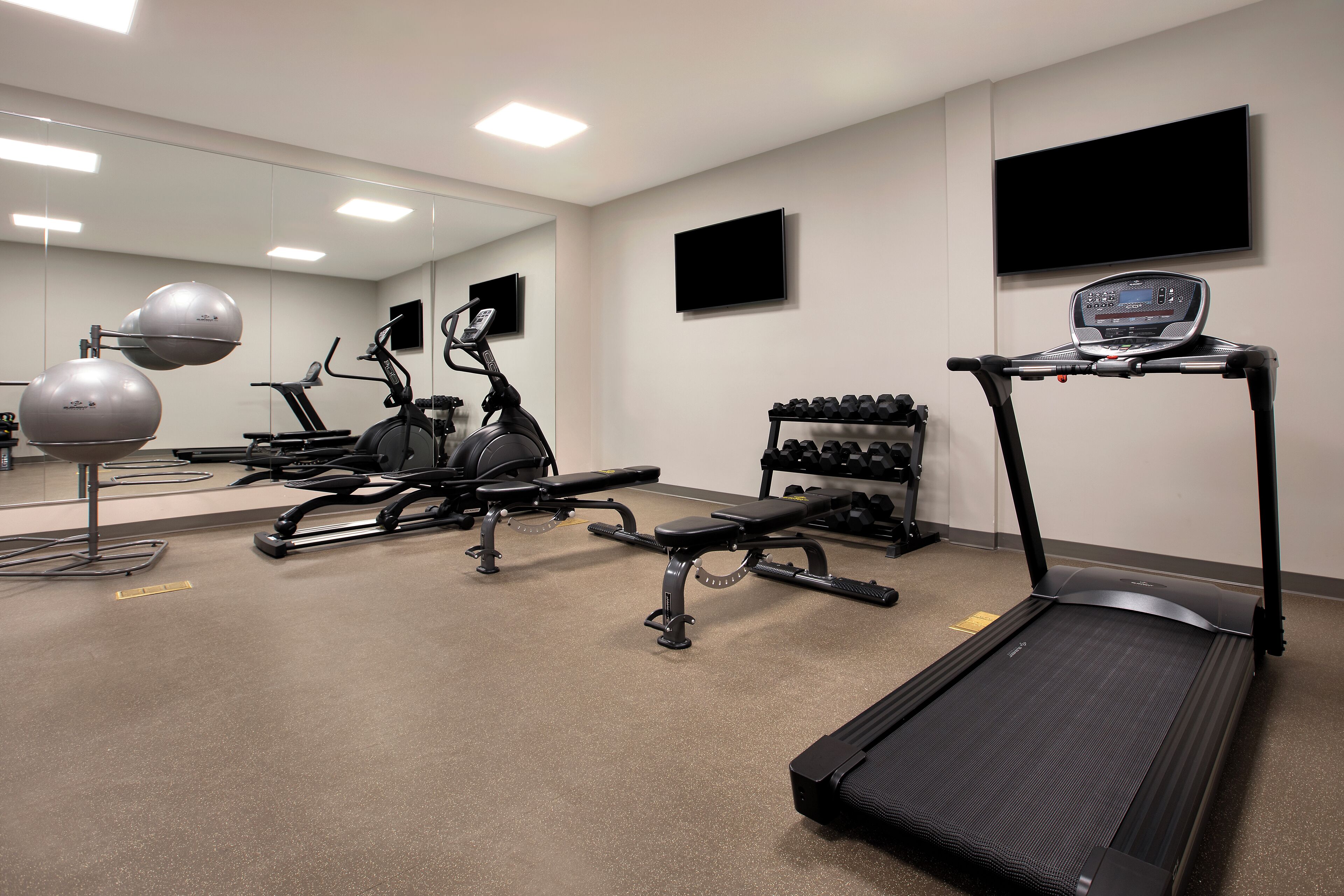 A gym with exercise equipment, a treadmill, and a mirror.