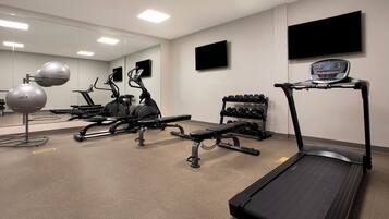 A gym with exercise equipment, a treadmill, and a mirror.