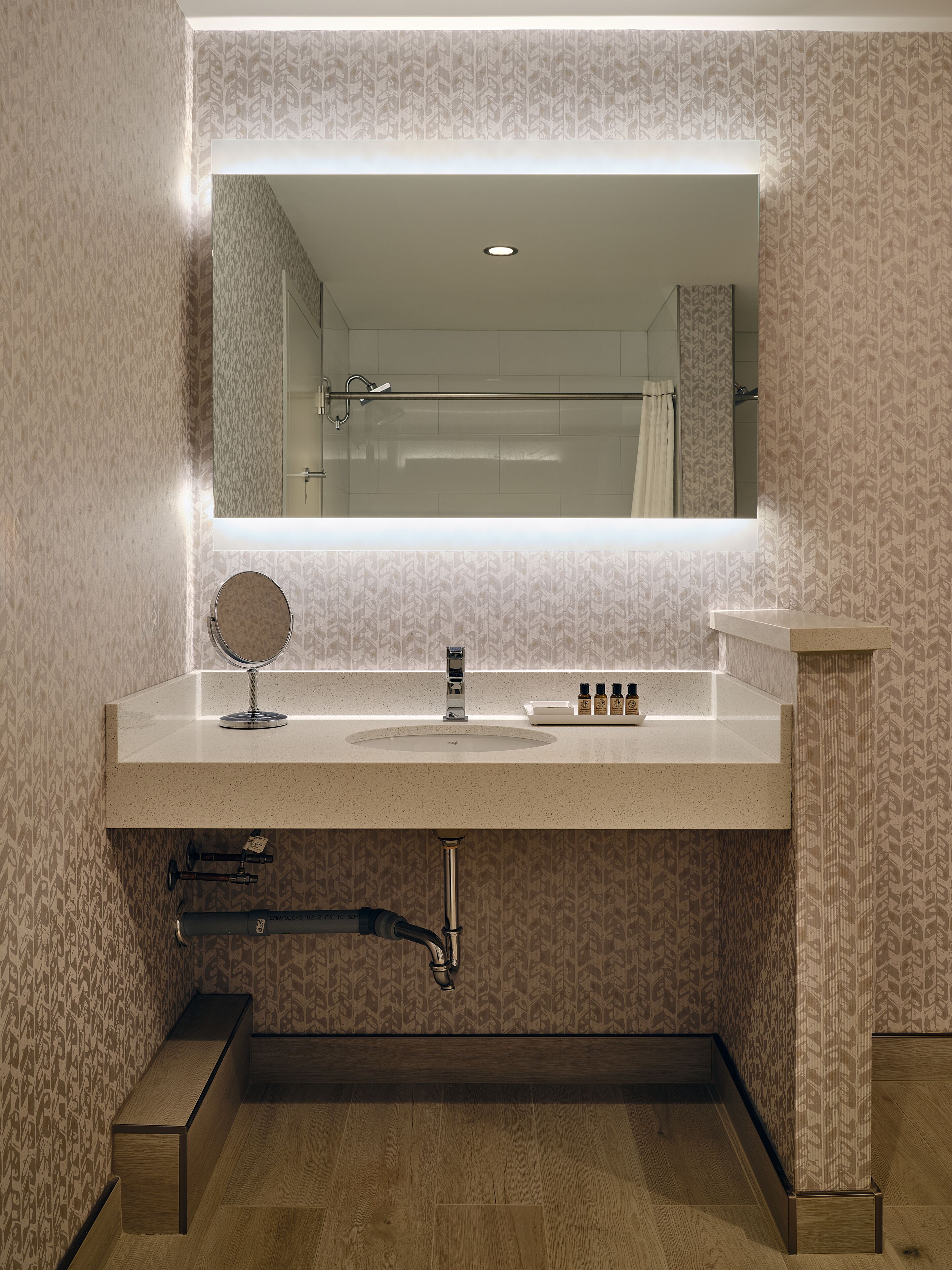 Une salle de bain équipée d’un meuble-lavabo, d’un miroir, d’un évier et d’un espace douche.