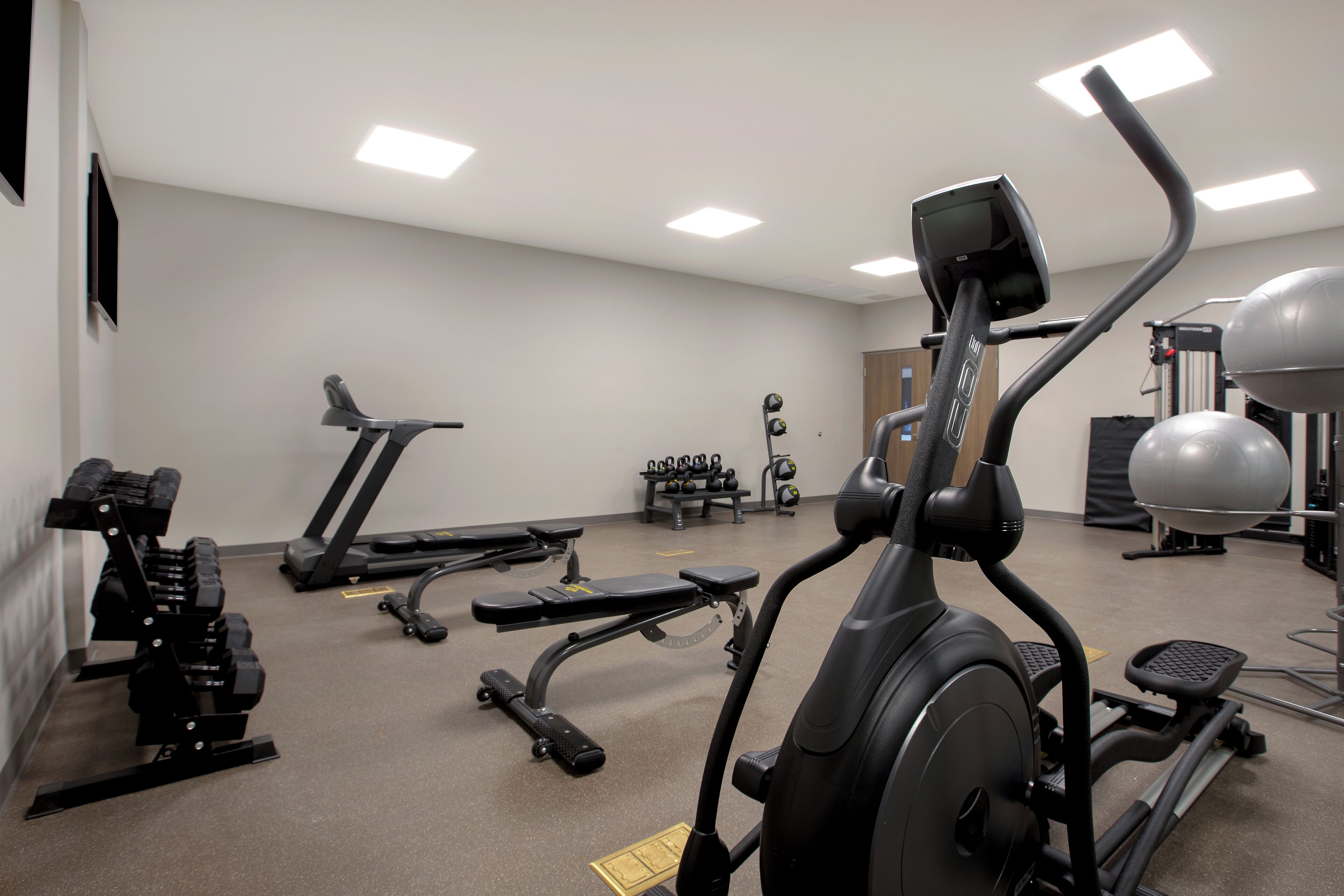 Une salle de sport équipée de divers appareils d’exercice, notamment des tapis de course, des appareils de musculation et des poids libres.