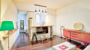 Een ruimtelijk ingerichte leefruimte met kitchenette, een eethoek en een zithoek met tafel en stoelen.