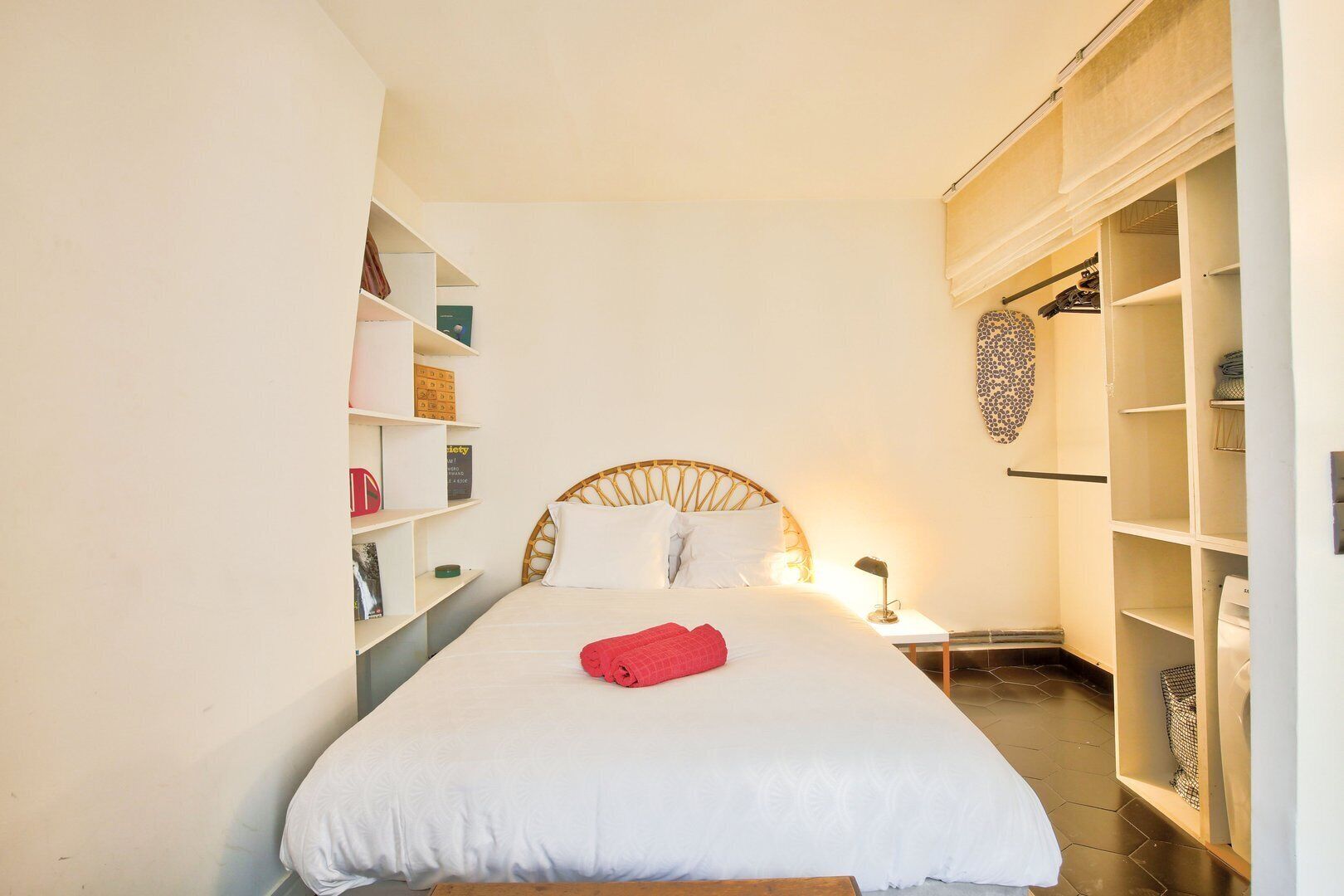A neatly arranged bedroom with a bed, bedside tables, and a wardrobe.