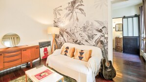 Een slaapkamer met een bed, een dressoir, een lamp en een gitaar.