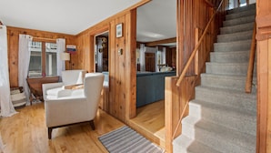 A wooden interior with a staircase, a sofa, and a dining area.