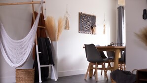 Una habitación con una hamaca, una mesa de comedor con sillas, un juego de mesa colgado en la pared y una lámpara colgante.