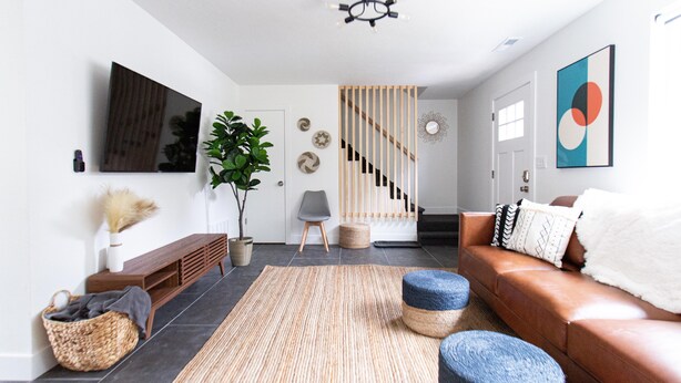 Una sala de estar moderna con un sofá, una mesa de centro, un televisor y una escalera.