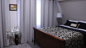 Une chambre à coucher avec un lit, une table de chevet, une lampe, un vase avec des fleurs et un tableau au mur.