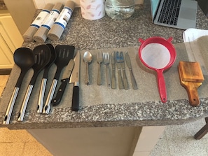 Un plan de travail de cuisine avec divers ustensiles, une passoire rouge et une brosse en bois.