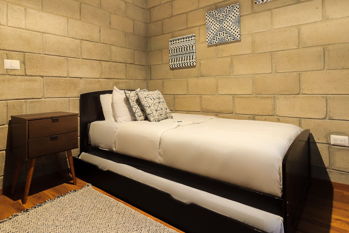 A bedroom with a bed, nightstand, and a small wooden dresser.