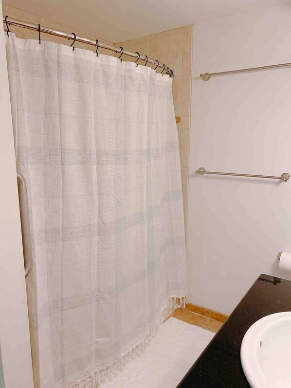 Ein Badezimmer mit Duschvorhang, Handtuchhalter und Waschbecken.