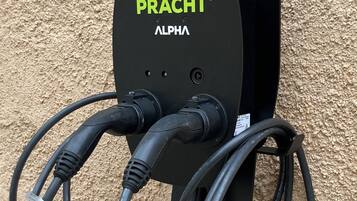 Une borne de recharge électrique noire de la marque « PRACT » et du modèle « ALPHA ».