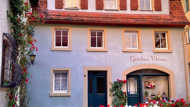 Un bâtiment à deux étages, avec une enseigne indiquant « Gästehaus Viktoria » et une porte bleue.