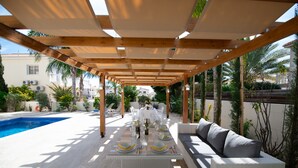 An outdoor patio with a pool, white furniture, and a pergola structure. - Graceful 3 Bedroom Agia Napa Villa with Pool (Agia Napa)