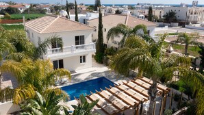 A residential area with a swimming pool, white balconies, and palm trees. - Graceful 3 Bedroom Agia Napa Villa with Pool (Agia Napa)
