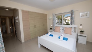 A bedroom with a large bed, a wardrobe, a nightstand, and a window with curtains. - Graceful 3 Bedroom Agia Napa Villa with Pool (Agia Napa)