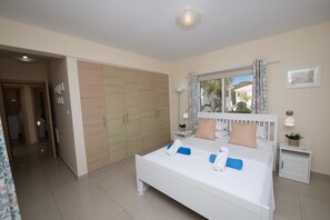 A bedroom with a large bed, a wardrobe, a nightstand, and a window with curtains.