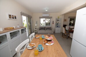 Ein Essbereich mit einem Holztisch, gedeckt für das Frühstück, einschließlich Croissants, Gebäck und Orangensaft.