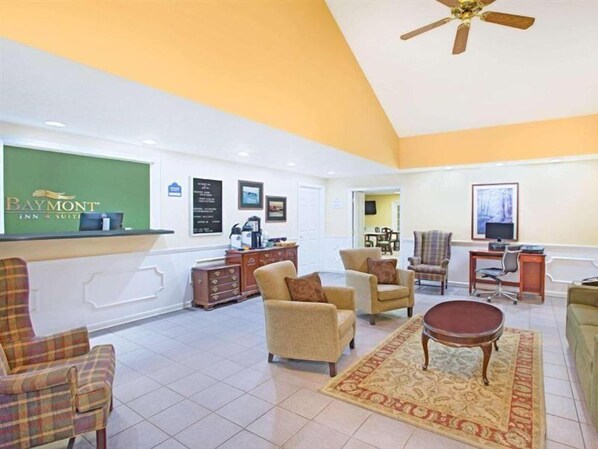 A lobby with a reception desk, several armchairs, a coffee station, and a television. - Baymont by Wyndham Forest City (Forest City)