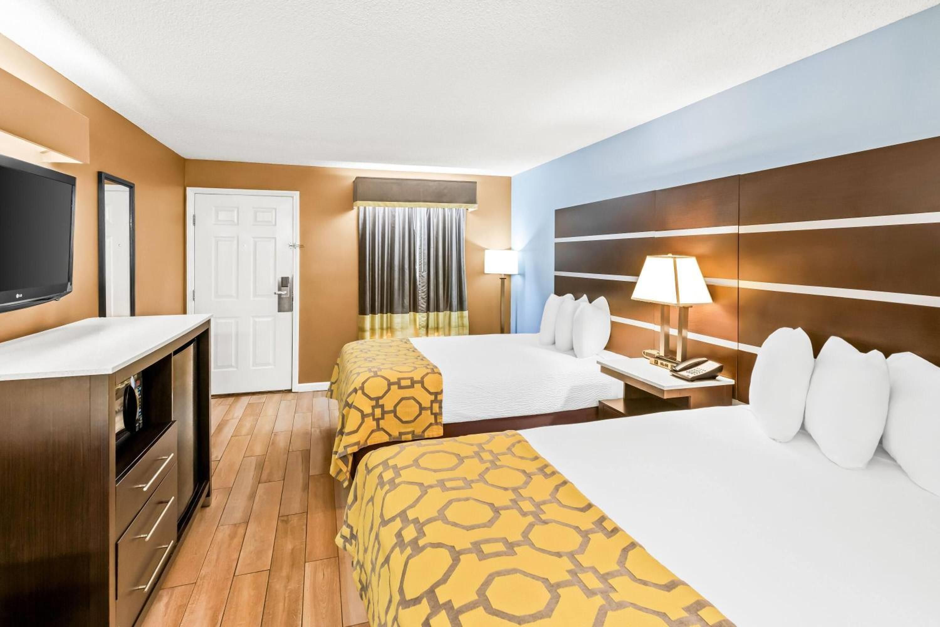 A hotel room with a bed, bedside table, lamp, and a TV.