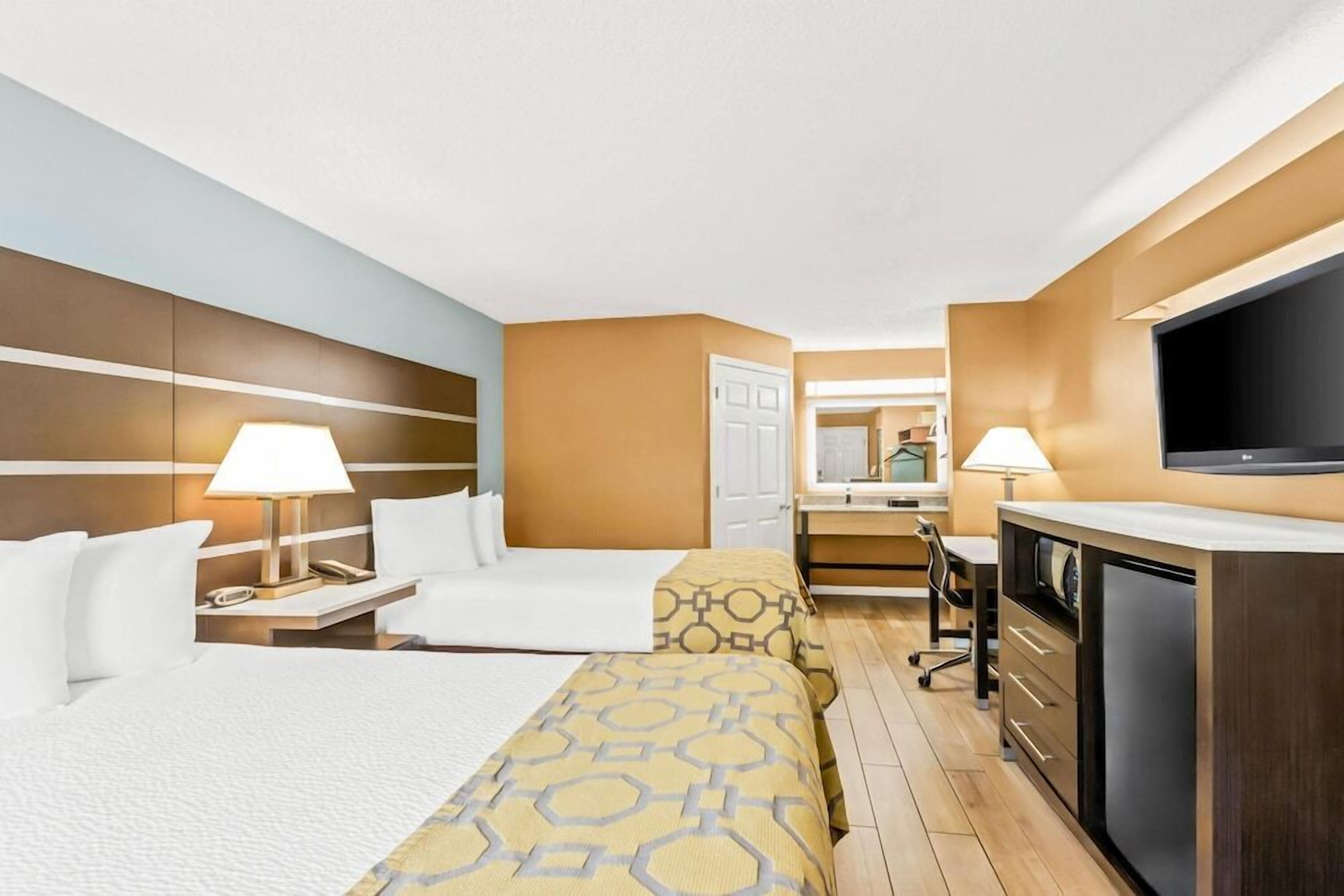 Hotellihuone, jossa on sänky, yöpöydät, työpöytä, tuoli, televisio ja vaatekaappi.