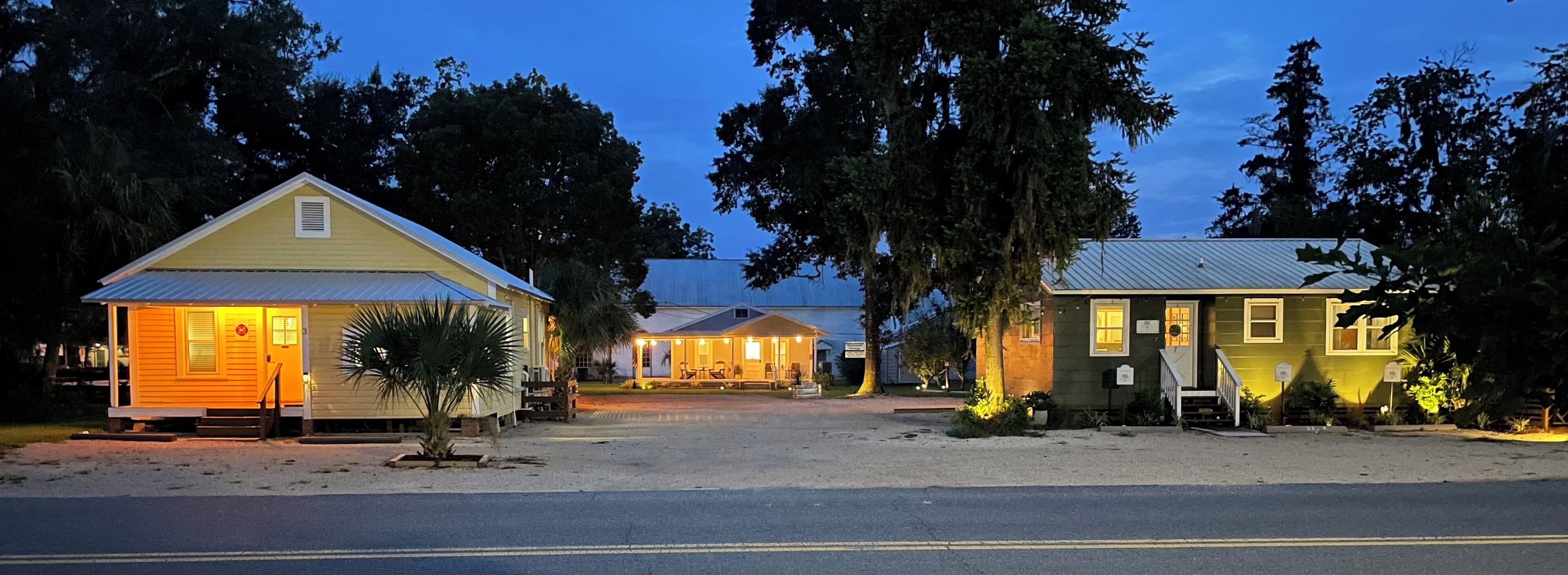 A row of small, yellow buildings with a single-story structure, each with a front porch and a small garden area.