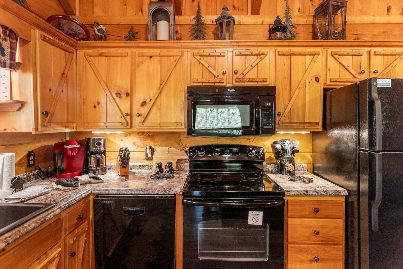 A kitchen with wooden cabinets, a microwave, stove, and refrigerator.