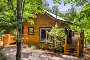 A wooden cabin with a porch, a small window, and a door.