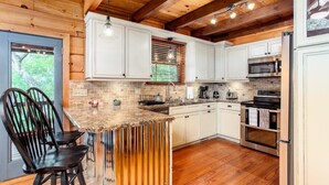 Una cocina con gabinetes blancos, techo de madera y una isla integrada con asientos.