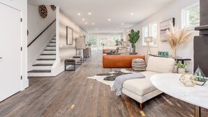 Ein geräumiger Wohnbereich mit Treppe, einer Couch, einem Couchtisch und einem Essbereich.