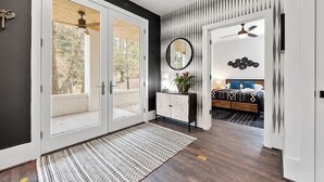 Ein modernes Schlafzimmer mit einem großen Bett, einem Nachttisch mit Spiegel und einem Deckenventilator.