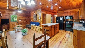 A wooden cabin interior with a dining area, kitchen, and living space. - New Hot Tub Grt WIFI Pool Table Sleeps10 Family (Blue Ridge)