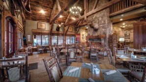 A rustic dining area with wooden tables and chairs, stone walls, and a chandelier. - New Hot Tub Grt WIFI Pool Table Sleeps10 Family (Blue Ridge)