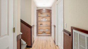 A narrow hallway with wooden flooring, white walls, and a built-in bookshelf with various items. - Hidden Gem Retreat | 2BR Basement |Near Mall of GA (Buford)