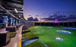 A stadium with multiple seating tiers, a green field with marked areas, and a large, illuminated structure in the distance. - 2BR Private Basement |Near Mall of GA & Dining Options Nearby (Buford)