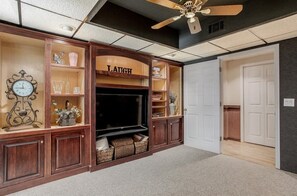 Relax in this stylish living room with an entertainment center featuring a large flat-screen TV and decorative glass-fronted shelves.