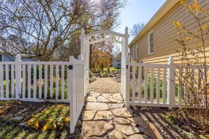 Enter a serene oasis through this beautifully landscaped entrance, featuring a charming stone pathway and lush greenery.