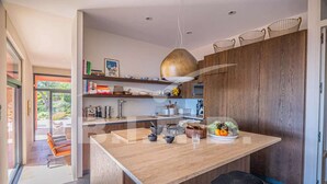 Una cocina moderna con una isla central, armarios de madera y una lámpara colgante.