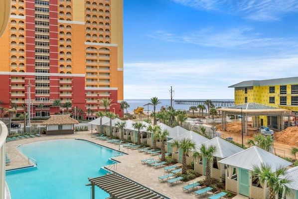 Ett semesterhotell med en swimmingpool, utsikt över stranden och en hög hotellbyggnad.