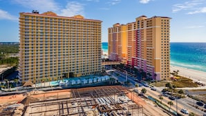 A high-rise hotel with multiple floors and balconies, located near a beach with clear blue waters. - Calypso Resorts Tower III Unit 310 (Panama City Beach)
