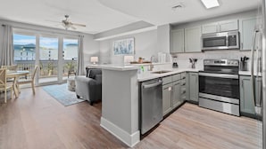 A modern kitchen with grey cabinets, stainless steel appliances, and a large island. - Calypso Resorts Tower III Unit 310 (Panama City Beach)