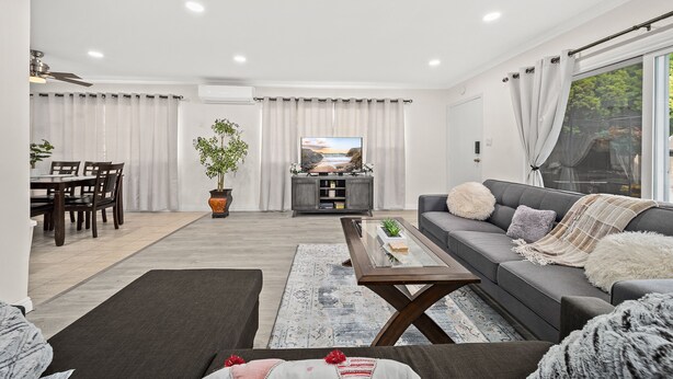 Una sala de estar moderna con un sofá gris, una mesita de centro y un televisor al fondo.
