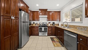 Una cocina con armarios de madera, electrodomésticos de acero inoxidable y encimera de granito.