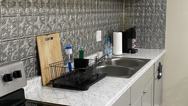 A kitchen with a black stove, a microwave, a sink, and a patterned backsplash.
