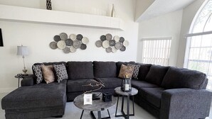 Ein modernes Wohnzimmer mit Ecksofa, rundem Couchtisch und Wandkunst.